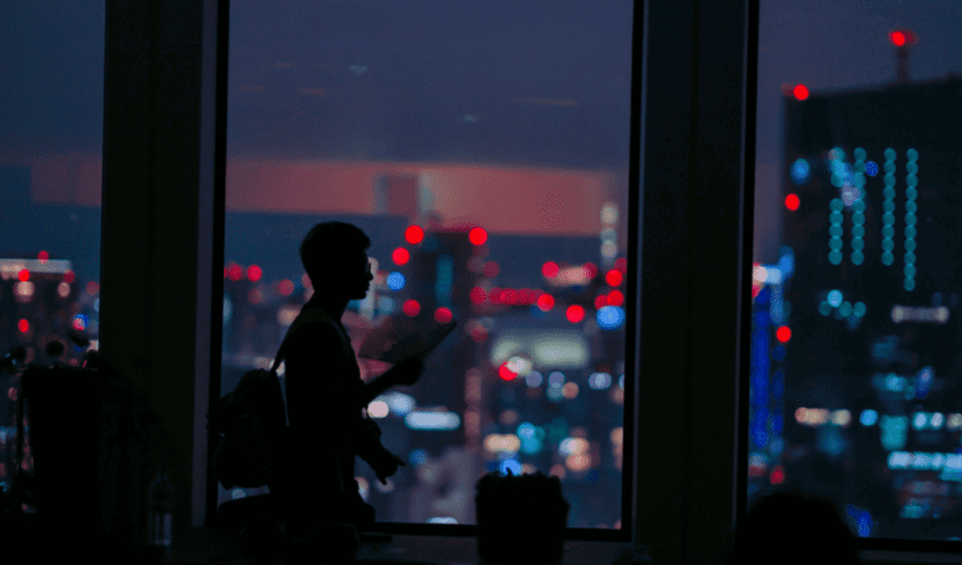 Silhouette of man walking in front of night cityscape