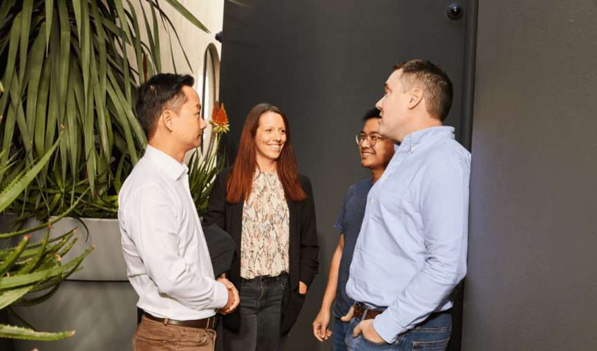 image of four people standing in a corridor smiling and chatting