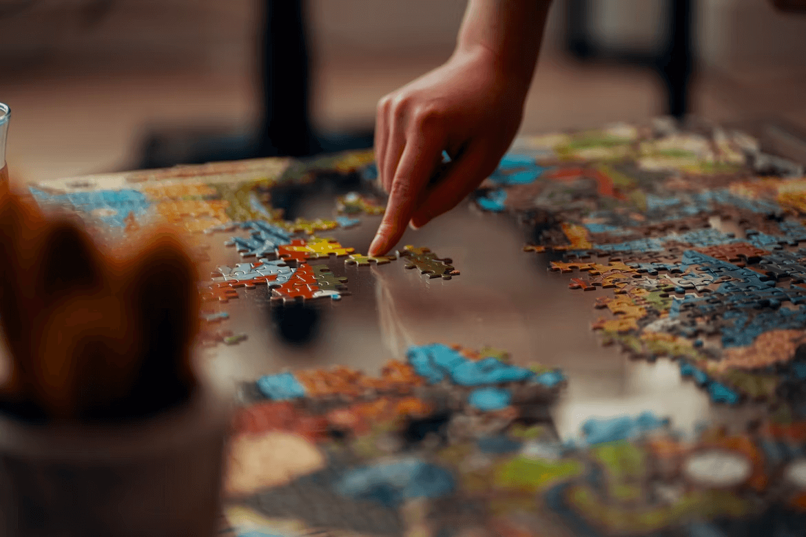 Hand moving a puzzle piece on a multicoloured puzzle