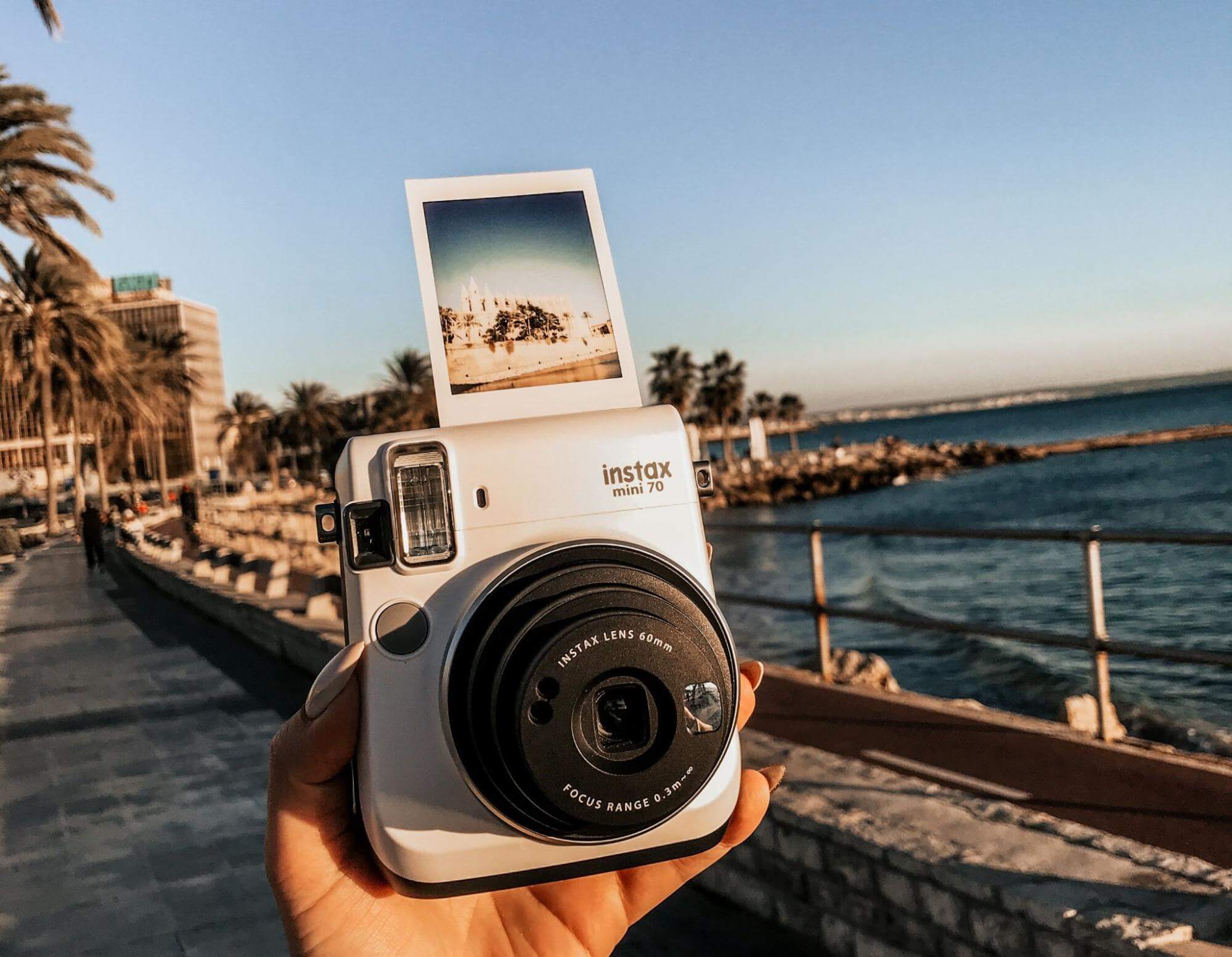 Hand holding a polaroid camera at the beach