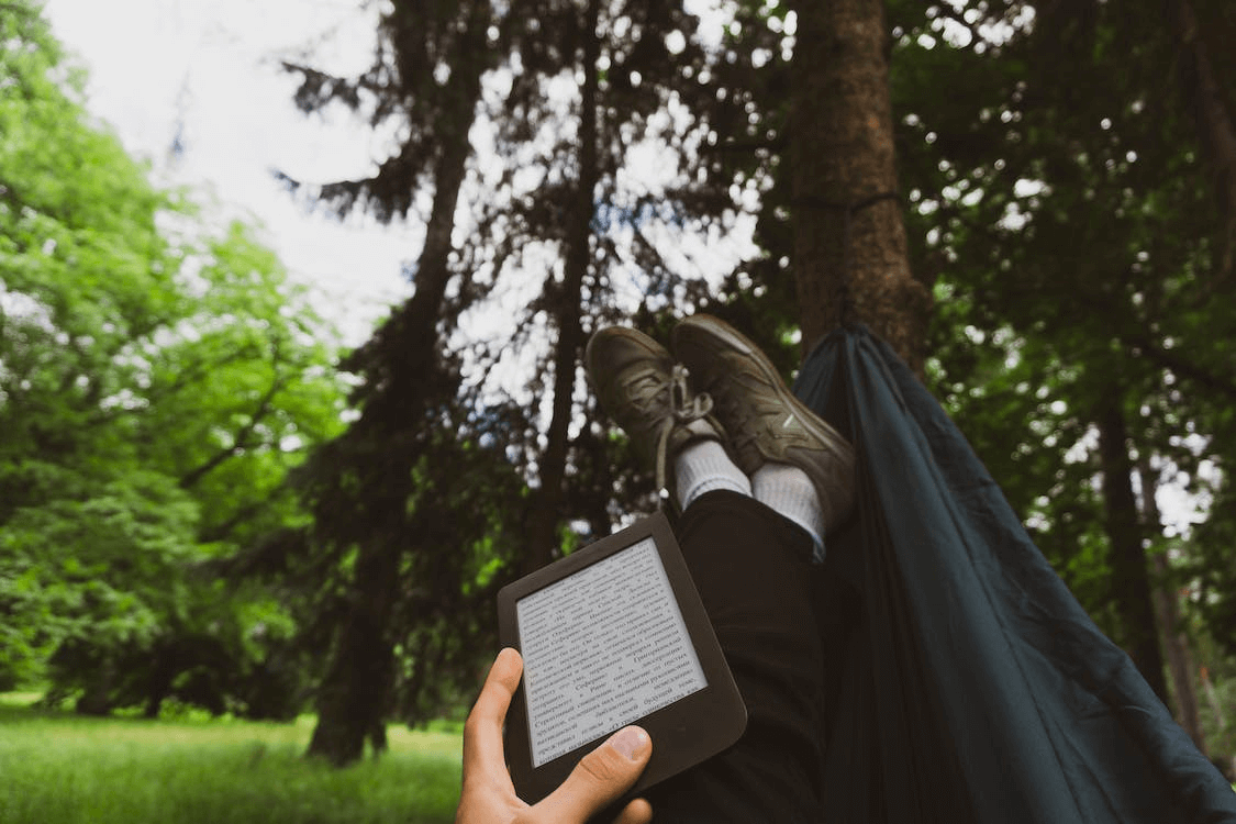 Person reading a Kindle in a forest