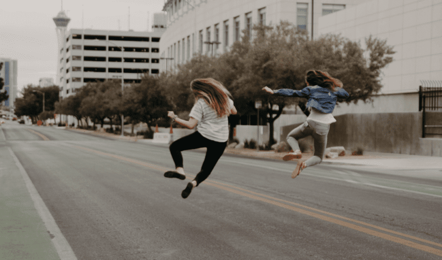 Two women jumping for joy on a city street