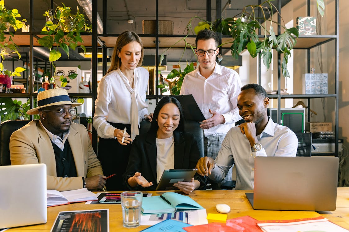 group of diverse employees laughing at something on the ipad