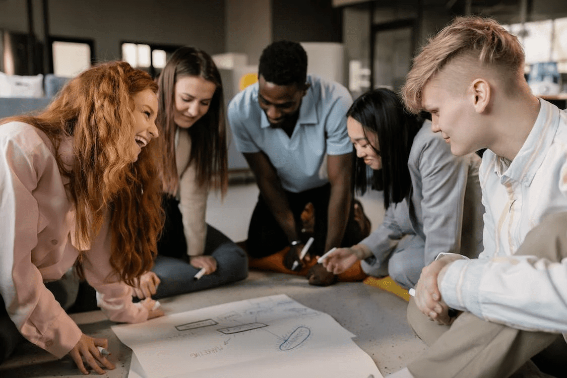 group of diverse employees huddle around a table brainstorming