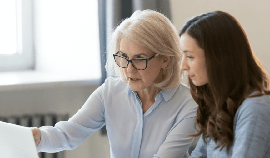 older woman discussing something on a laptop with a younger woman